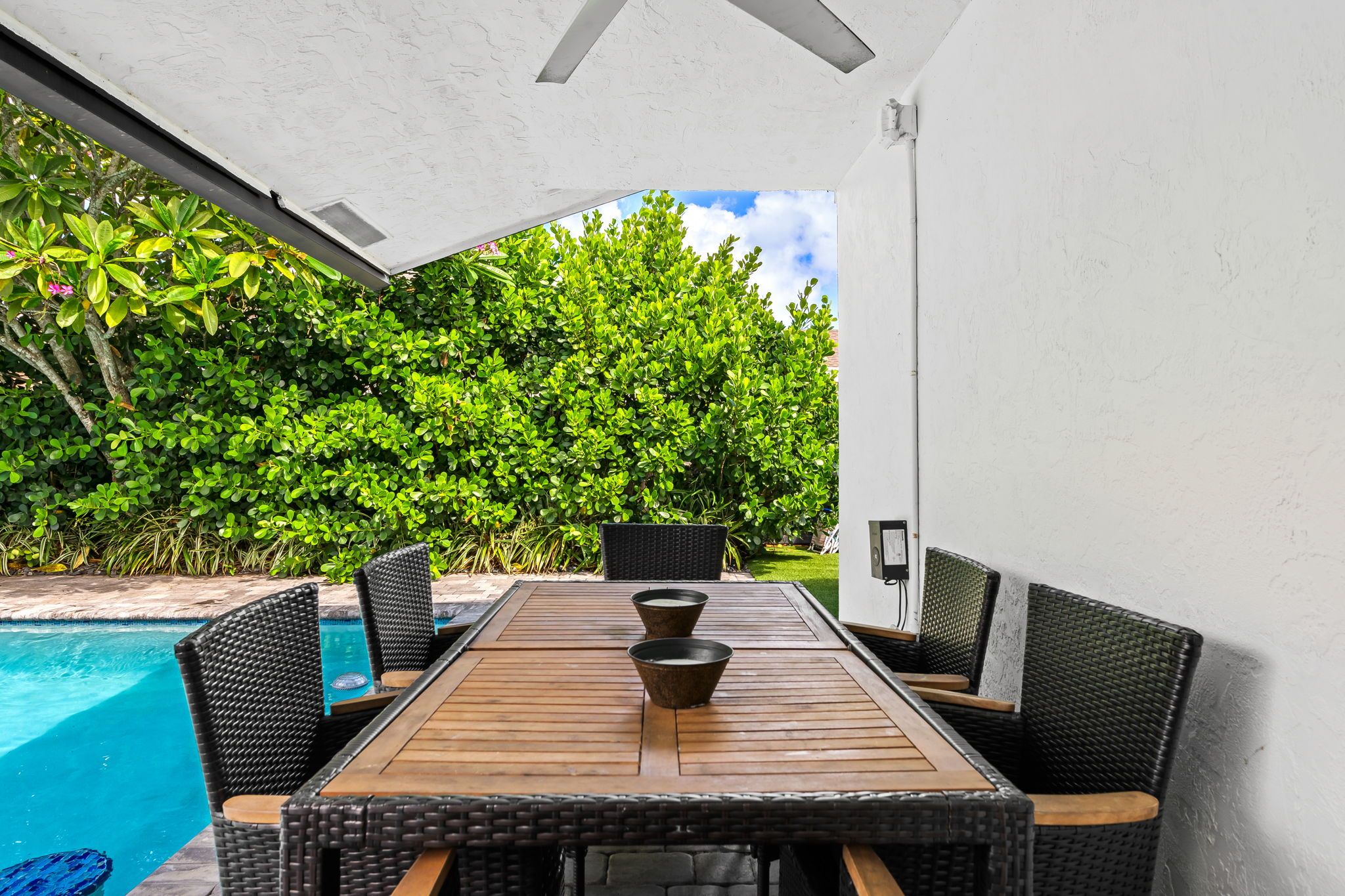 Uma área de refeições ao ar livre com piscina, rodeada por vegetação exuberante.