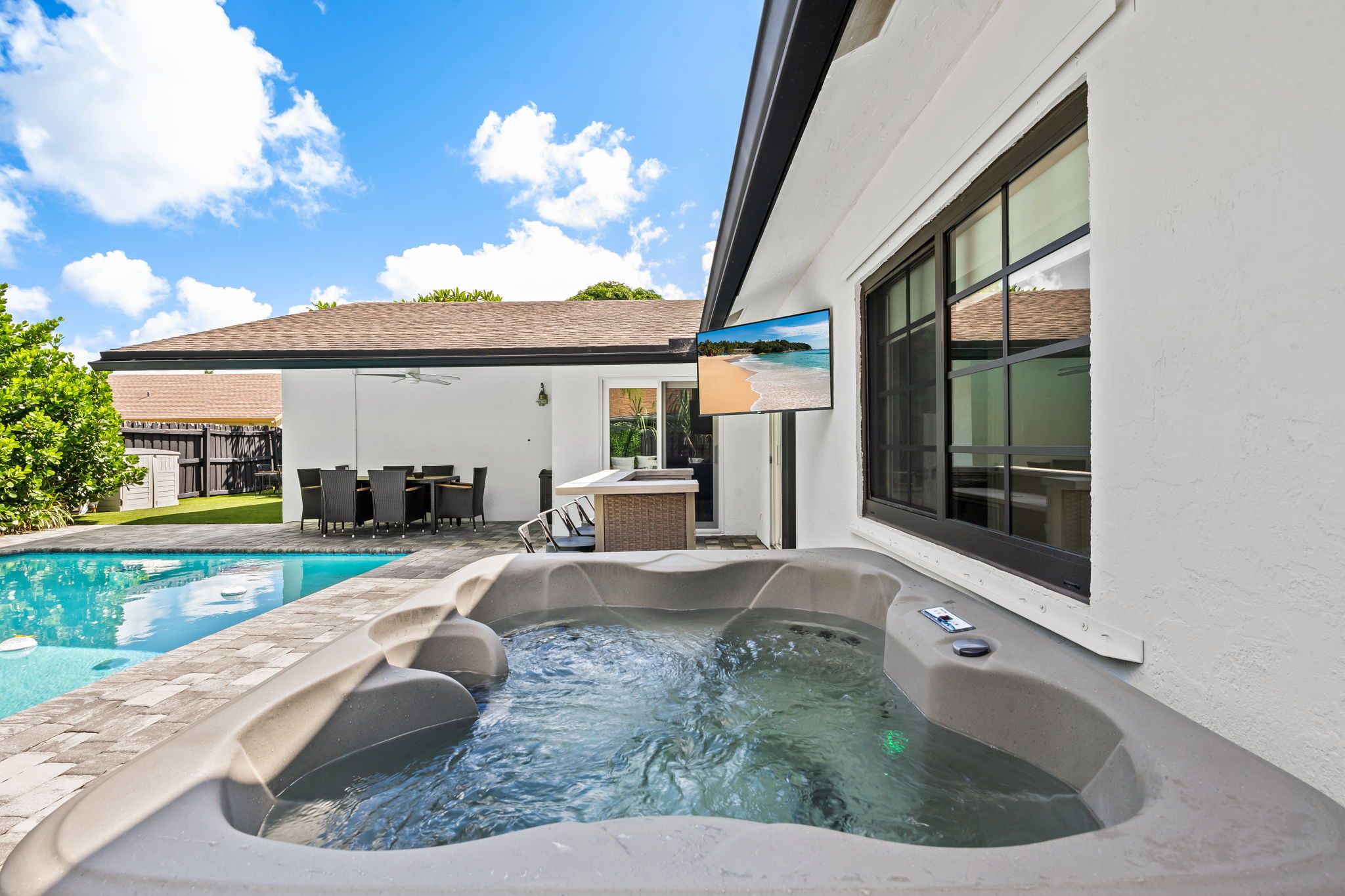 Ein Schwimmbecken mit Whirlpool und einer Terrasse mit Gartenmöbeln.