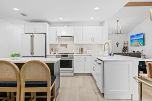 A modern kitchen with white cabinetry, stainless steel appliances, and a central island. - Casita Delray Oasis: 4BR with Pool, Hot Tub, BBQ, Firepit, Pool Table (Delray Beach)