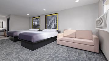 Une chambre d’hôtel avec deux lits, un canapé et une grande fenêtre équipée de stores.