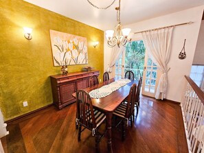 Enjoy meals in this elegant dining area with a wooden table set for six, surrounded by classic chairs and a beautiful floral painting.
