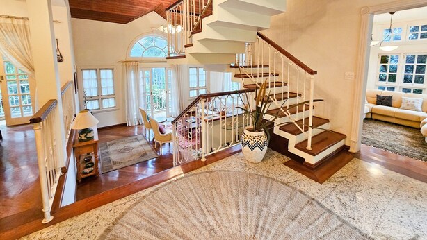 Un vaste espace de vie agrémenté d’un escalier en bois, d’un grand tapis et offrant une vue sur l’extérieur.