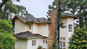 Une maison à deux étages, dotée d’une cheminée en pierre, d’un revêtement extérieur blanc et d’un toit en tuiles.