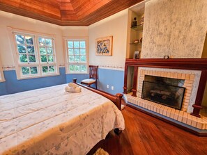 Cozy retreat with a large bed, fireplace, and a chair by the fire.