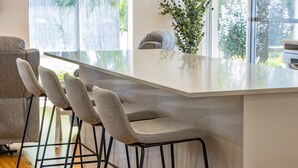 A modern kitchen with a large island, bar stools, and a view of greenery outside. - Peppermint Rise - a luxurious retreat in Peppermint Grove Beach, WA. (Peppermint Grove Beach)