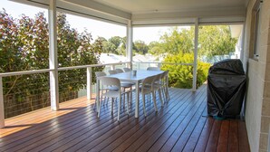 A covered outdoor area with a wooden deck, a table with chairs, and a barbecue grill. - Peppermint Rise - a luxurious retreat in Peppermint Grove Beach, WA. (Peppermint Grove Beach)