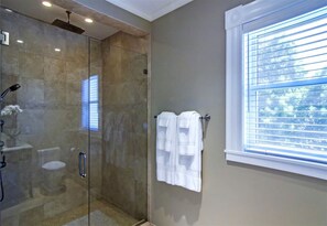 Un baño con ducha de vidrio, inodoro y toallero con toallas.