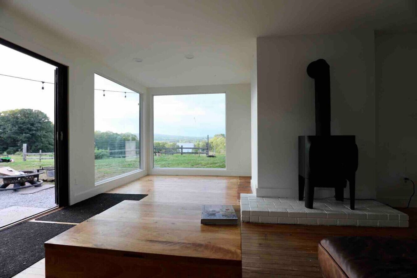 A modern living room with a fireplace, large windows, and a view of the outdoors.