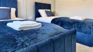 Une chambre d’hôtel avec deux lits, chacun doté d’une tête de lit bleue et d’oreillers blancs. Des serviettes sont posées sur les lits.