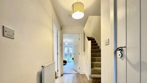 Un couloir avec un plancher en bois, un radiateur et un escalier menant à une autre pièce.