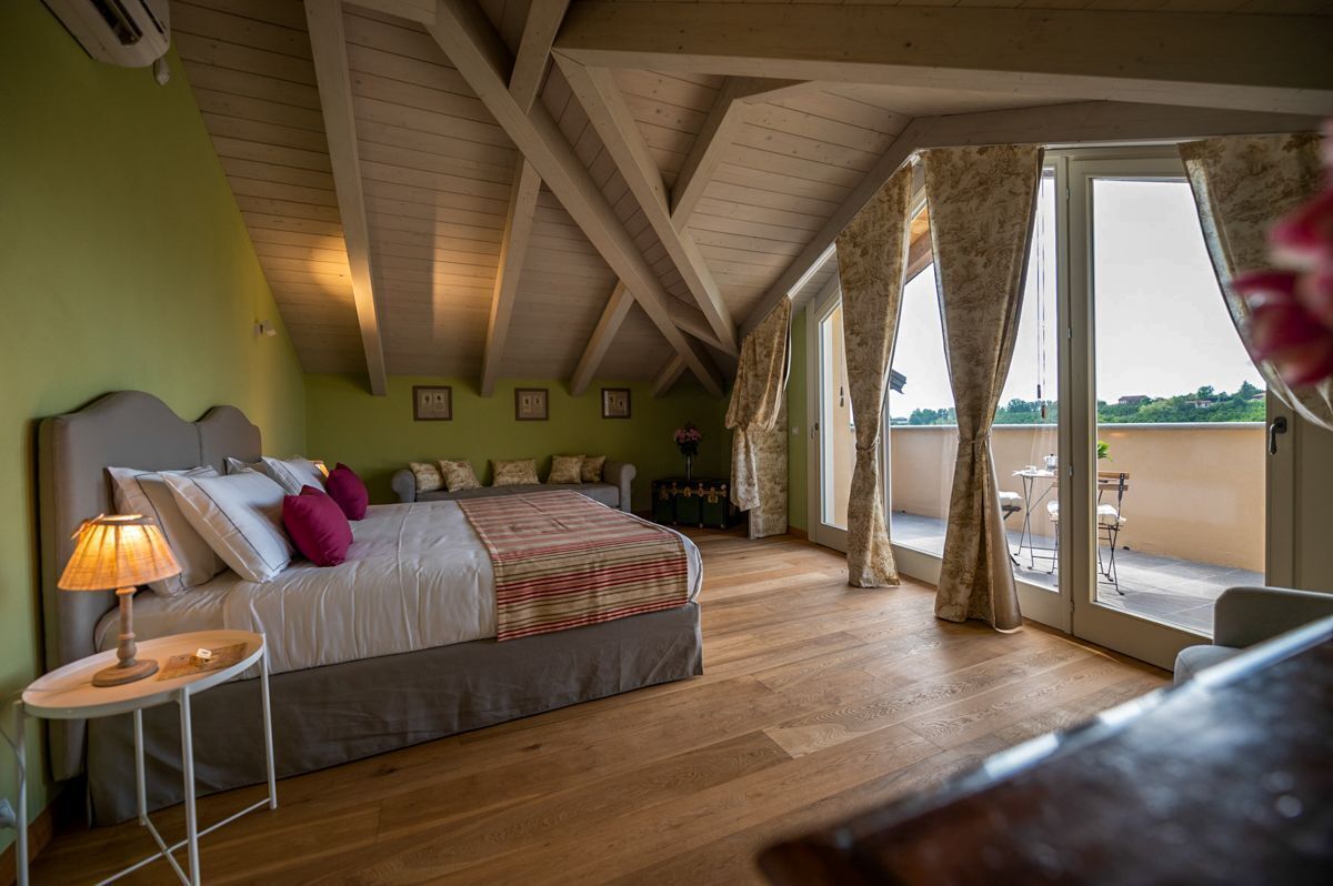 A bedroom with a large bed, a nightstand, a lamp, and a view of the outdoors through a sliding glass door.