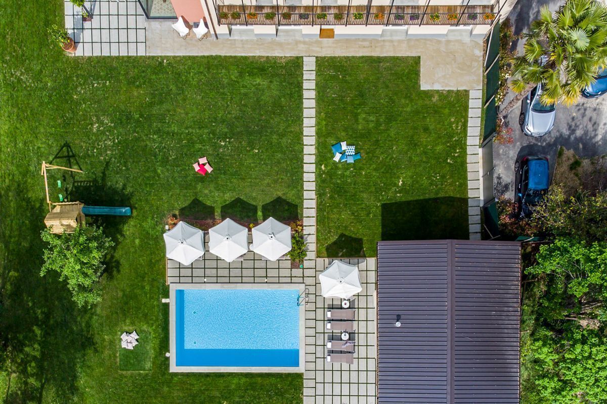 Vue aérienne d’une propriété résidentielle dotée d’une piscine, d’un espace de détente extérieur et d’un patio couvert.