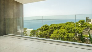A modern balcony with a glass railing overlooking a coastal landscape with trees and a view of the sea. - Villa Rora - Four Bedroom Villa, Sleeps 8 (Brela - Krug)