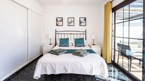 Una camera d'albergo con un letto, due comodini, una finestra con tende e un'opera d'arte appesa al muro.