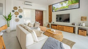 Een moderne woonkamer met een bank, televisie en decoratieve muurkunst.
