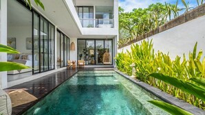 Een modern huis met een zwembad, grote glasramen en een balkon.