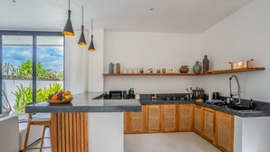 Een moderne keuken met een centraal eiland, houten kastjes en een zwart aanrecht.