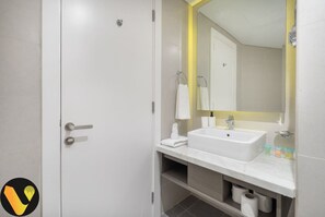 Ein modernes Badezimmer mit einem weißen Waschbecken, Spiegel und Handtuchhalter.