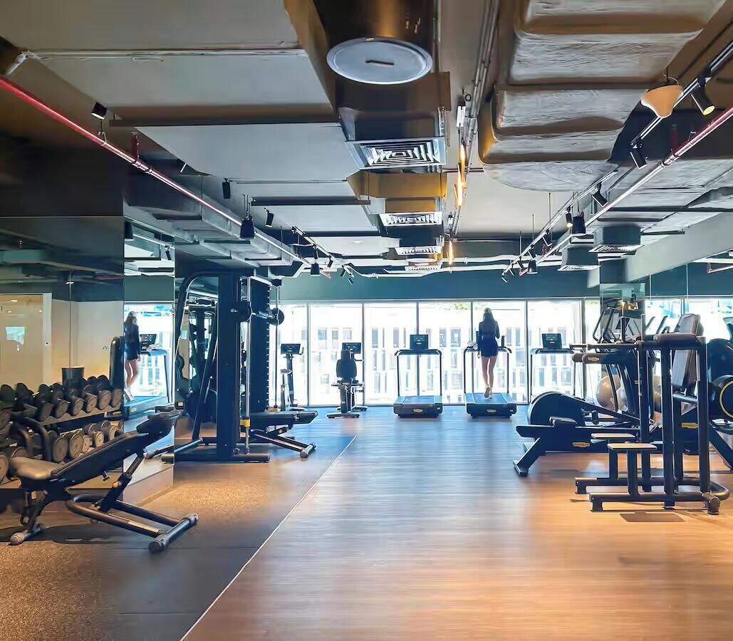 Une salle de sport équipée de tapis de course, d’appareils de musculation et d’haltères.