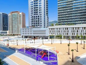 Una zona urbana moderna con edificios altos, una cancha deportiva y palmeras.