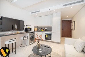 A modern kitchen with a central island, a dining area with a round table, and a white sofa.