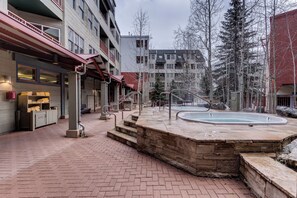 Une cour d’hôtel avec une piscine, des marches en pierre et un espace salon abrité.