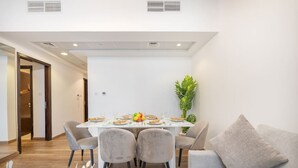 A modern dining area with a white table set for four, surrounded by grey upholstered chairs.