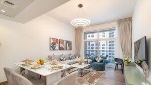 A modern living room with a dining area, large windows, and a flat-screen TV.