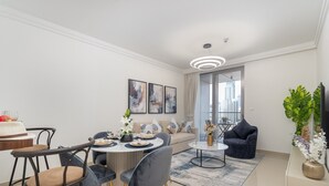Ein modernes Wohnzimmer mit Essbereich, ausgestattet mit einem runden Tisch, Sofas und einem großen Fenster mit Blick auf die Stadt.