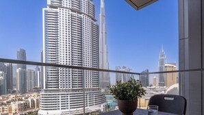 Ein Balkon mit Tisch, Stuhl und Topfpflanze, mit Blick auf eine Skyline mit modernen Wolkenkratzern.