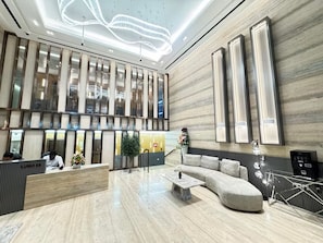 Een moderne lobby met een receptiebalie, een zithoek en een grote wand met verticale panelen.