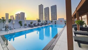 A rooftop pool with lounge chairs and umbrellas, surrounded by tall buildings. - Vogue, JVC Luma22 East near Circle Mall (Dubai)