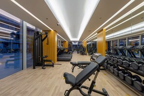 Een sportschool met loopbanden, gewichtbanken en dumbbells.