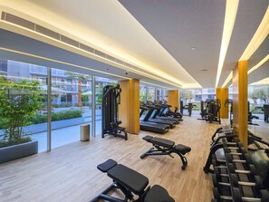 A modern gym with treadmills, weight benches, and exercise equipment.