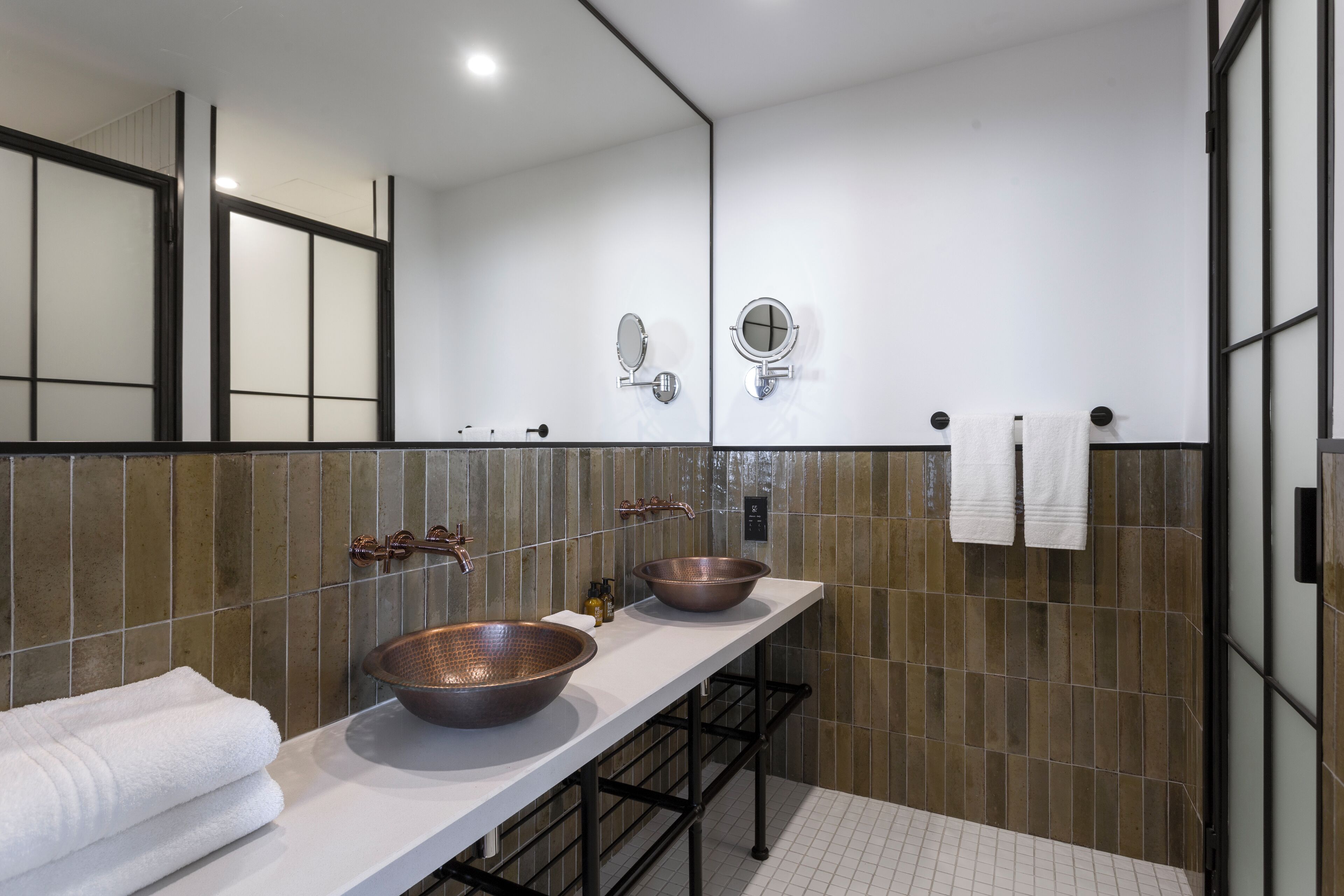 Un baño moderno con dos lavamanos, un espejo grande y un perchero para toallas.