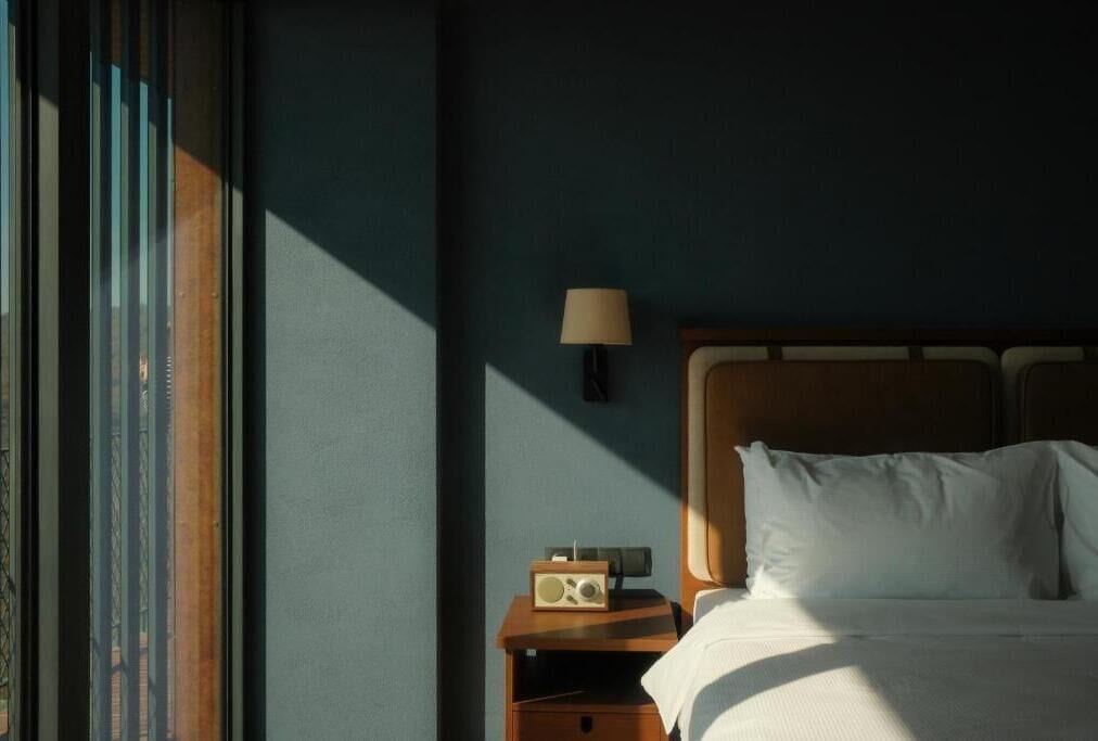 Une chambre d’hôtel avec un lit, une table de chevet avec une lampe et une radio.