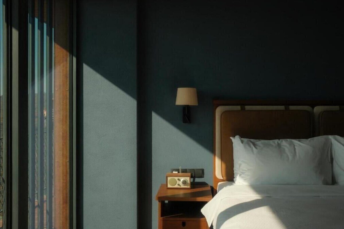 A hotel room with a bed, a nightstand with a lamp, and a radio.