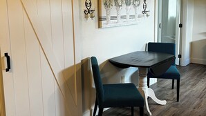 Ein Essbereich mit Holztisch und zwei Stühlen, einer Schiebetür im Scheunenstil und einem gerahmten Bild an der Wand.