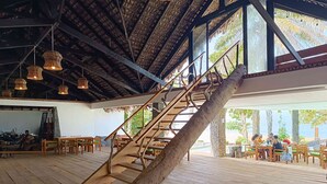 A wooden staircase with a natural design, leading to an outdoor area with wooden tables and chairs.
