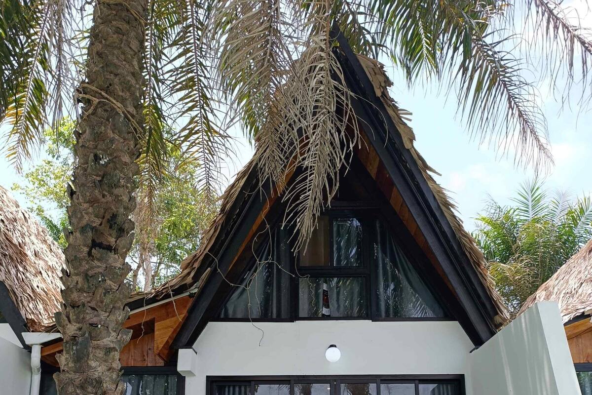Une villa moderne dotée d’une piscine, de deux fauteuils de jardin et d’un banc en bois.