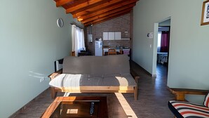 Una sala de estar acogedora con techo de madera, un sofá, una mesita de centro y vistas al área de la cocina.