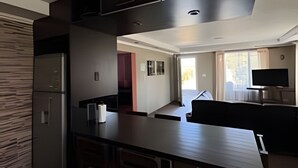 Una cocina moderna con armarios oscuros, una isla central con taburetes y un horno empotrado.