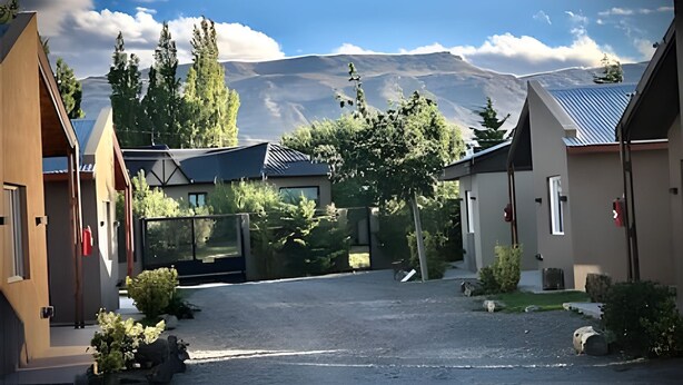 Un edificio moderno con un camino de grava y una montaña al fondo.