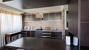 Una cocina moderna con una isla grande, muebles oscuros y un microondas.