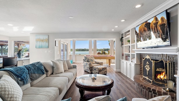 A spacious living room with a large TV, a fireplace, and a pool table. - Luxury Hideaway - Lakefront - Mini Golf, Pool + More! (Seffner)