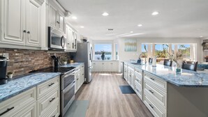 A modern kitchen with white cabinets, a granite countertop, and a view to the outside. - Luxury Hideaway - Lakefront - Mini Golf, Pool + More! (Seffner)