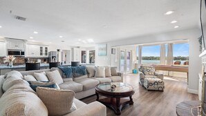 A spacious living area with a large sectional sofa, a round coffee table, and a view of the outdoors. - Luxury Hideaway - Lakefront - Mini Golf, Pool + More! (Seffner)