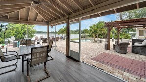 A covered patio with outdoor seating, a pool, and a view of the water. - Luxury Hideaway - Lakefront - Mini Golf, Pool + More! (Seffner)