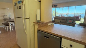 Une cuisine compacte équipée d’un réfrigérateur, d’un lave-vaisselle et d’un petit plan de travail.