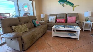 Un salon avec un canapé marron, une table basse blanche et une décoration murale représentant des poissons turquoise.